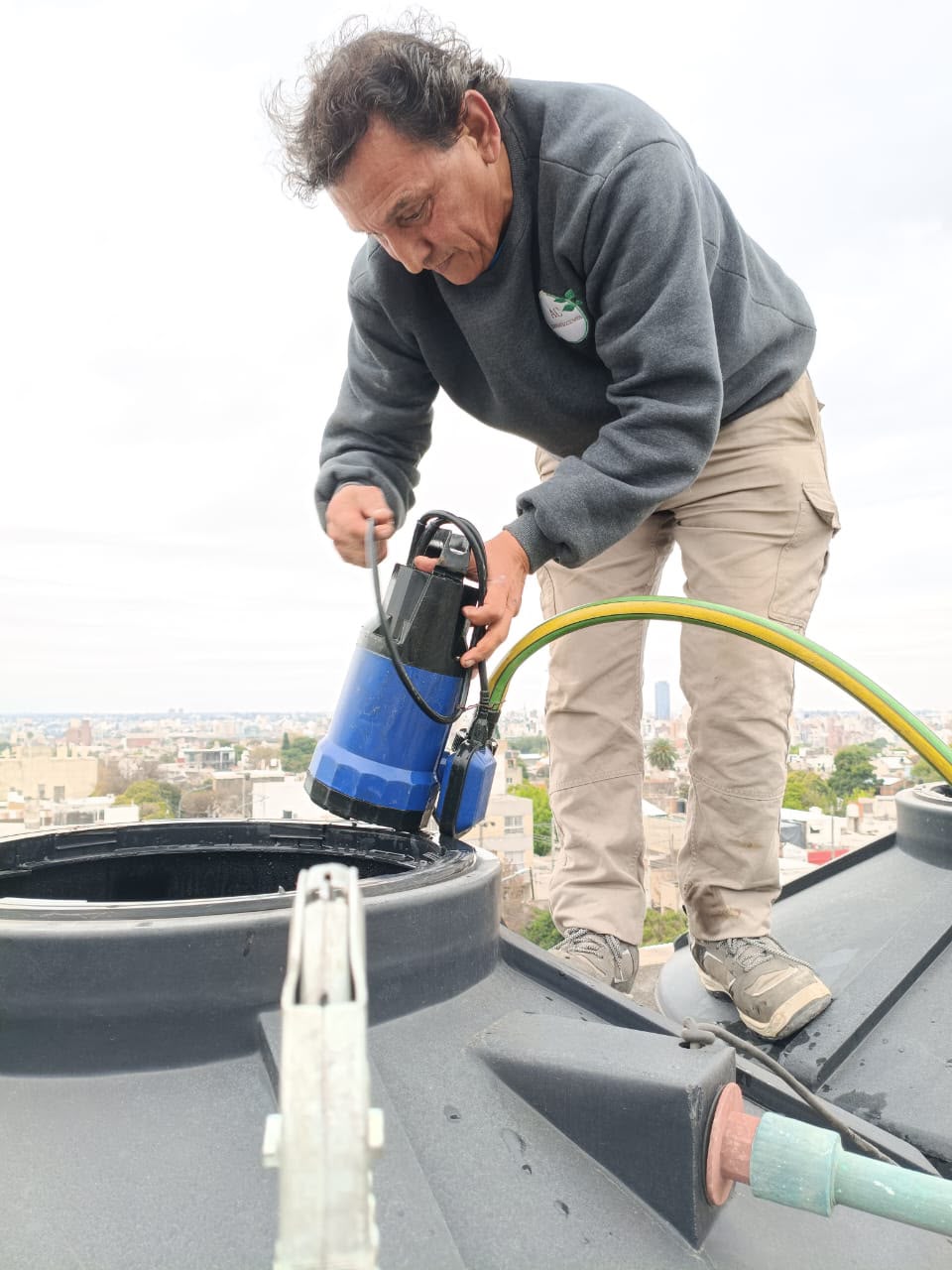 Técnico de AC Desinfecciones colocando la bomba para limpiar un tanque de agua